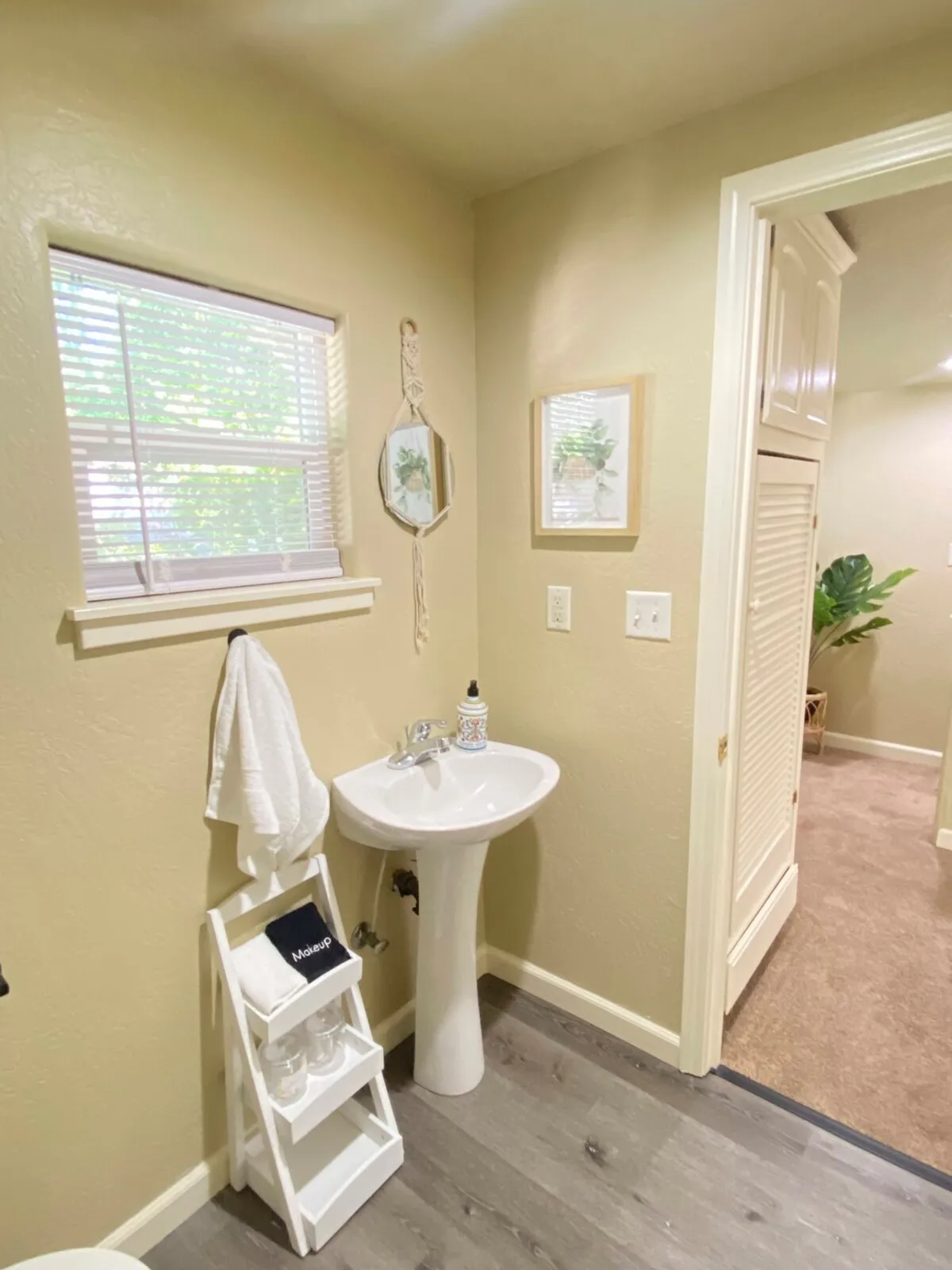 This image spotlights a pedestal sink with mirrored wall decor and a shelf stocked with glass containers, creating an inviting and calm ambiance suitable for personal grooming and relaxation. Thoughtful decor details enhance the sense of comfort and quality.