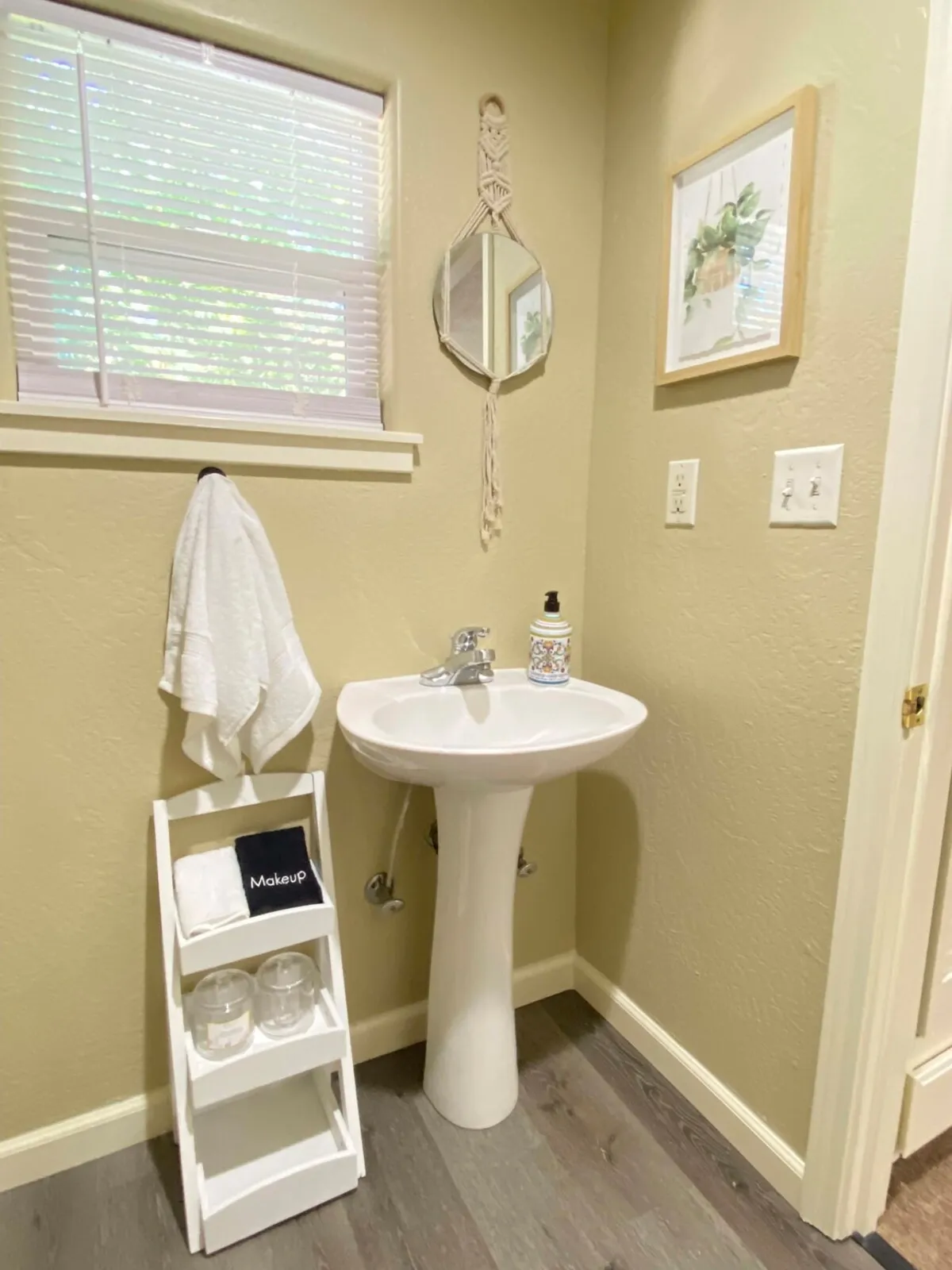 A bright, refreshing bathroom scene with a modern sink, a large mirror, and tasteful wall art. Natural morning light streams through the window, creating a serene environment perfect for personal moments and morning routines.