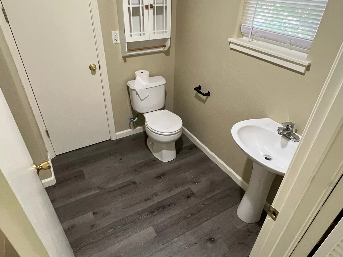 This image features a minimalistic bathroom with a toilet, sink, and a storage cabinet, emphasizing practicality and organizational space. The simple and uncluttered design reinforces the sense of privacy and convenience described in the text.