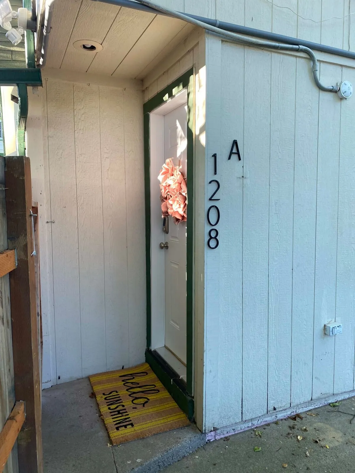 A close-up view of a front door adorned with a welcome mat and wreath, set against a friendly and tidy exterior. The image radiates an inviting, homey feel and hints at ease of entry for guests.